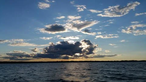 Sun hidden behind clouds above lake Foto stock
