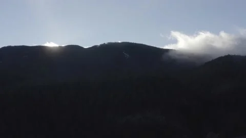 Sun hidding behind mountain. Cold and clear day. Some snow and fog. Aerial shot. Stock Footage 158557174