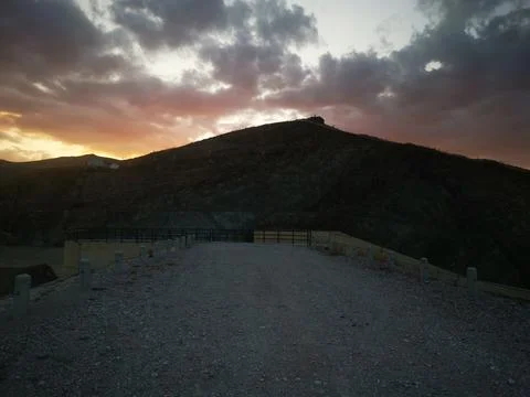 Sun hides behind clouds, does not blind rays visible on a paved and asphalt road Stock Photos
