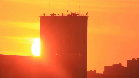 The sun hides behind tower building Stock Footage 149215387