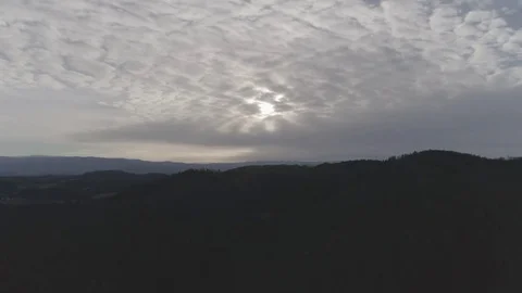 Sun is hiding behind cloud formation in the sky over a green landscape, 4K Stock Footage 73851023