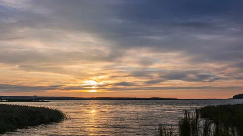 The sun, hiding  behind dense stripe of clouds, move down to horizon line Stock Footage 144318195