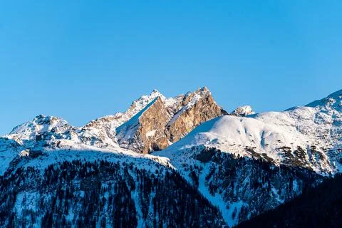 Sun hitting sharp mountain peaks covered in snow Foto stock