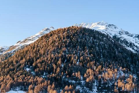 Sun hitting sharp mountains covered in snow Stock Photos
