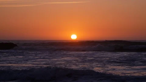 Sun on horizon at sunset over ocean with waves in foreground Stock Footage 104684260