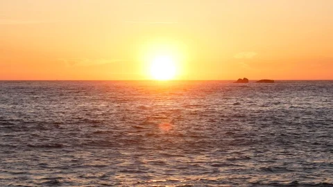 Sun on horizon at sunset over the ocean with reflections Video stock 107995320