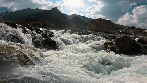 The sun illuminates a bubbling mountain stream among rocks Vídeo Stock 317706207