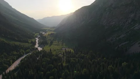 Sun illuminating mountain valley with lush green forest and river 스톡 동영상 312447785