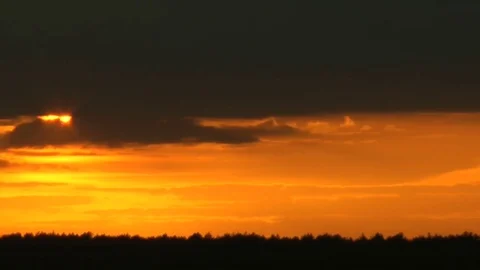 The sun leaves low overcast and comes for the horizon hiding behind clouds. Видео 70068161