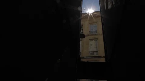 Sun with light flares over an old building seen from a narrow dark alley in Vídeos de archivo 110701770