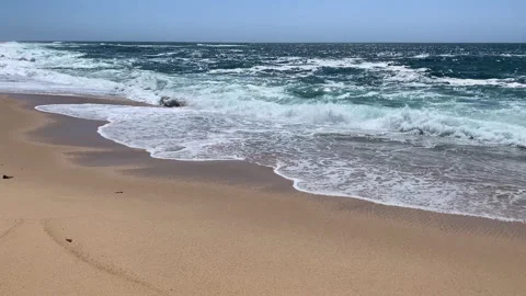 Sun light glistening on ocean as waves break on beach in summer Stock Footage 240671487