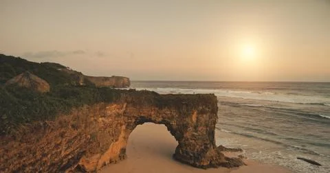 Sun light over green cliff at sand beach washed by ocean bay waves. Nobody Fotos Stock