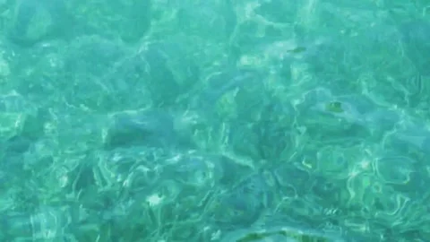 Sun light reflects on rippling clear turquoise ocean water Stock Footage 329751997