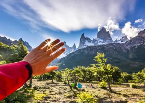 Sun light through man's hand at sunset near fitz-roy mountain in patagonia Stock Photos