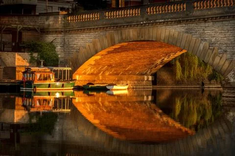 Sun lighting workman bridge in Evesham with boats moored underneath Stock Photos