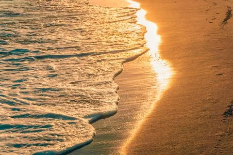 The sun lights are shining on the waves at sunset. Golden tones. Stock Photos