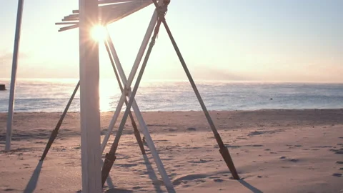 The sun lights through construction from paddles on the beach near the sea edge Stock Footage 168536604