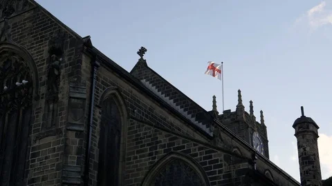 Sun-lit flag of England waves over historic St Michael's Church-Haworth Stock Footage 96694289