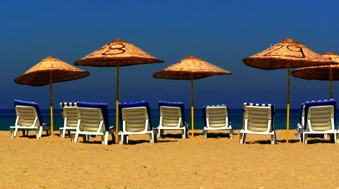 Sun loungers on an empty beach with clear blue sky 2 Stock Footage 938374