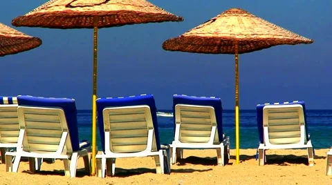 Sun loungers on an empty beach with clear blue sky 4 Stock Footage 938487