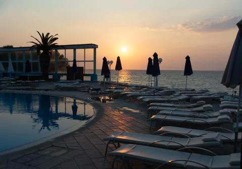 Sun lounges overlooking infinity pool and beach at sunset in a resort. Rhodes Stock Photos