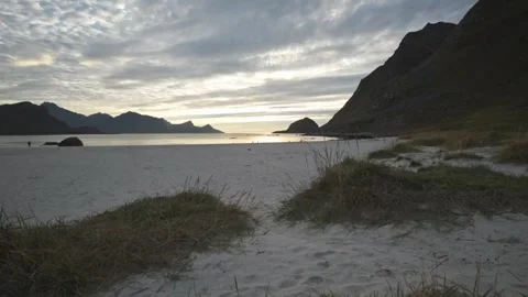 Sun low over the bay beyond dune grass at Unstad, Vestvagoy, Lofoten, Norway Stock Footage 344535781