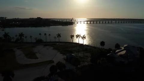 Sun Low Over Palm-Lined Marina and Causeway Bridge on Quiet Florida Waterway Stock Footage 337439487