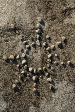 The sun made up of smooth pebbles on a stone surface Stock Photos