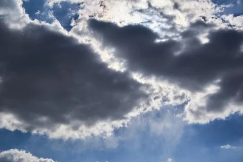 The sun makes the way through dark clouds in the blue sky Stock Photos