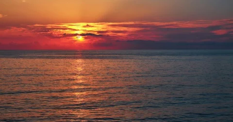 Sun moving down to the sea through clouds making red light 4k Stock Footage 114393733