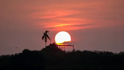 The sun is one big orange fireball as it slowly rises above horizon. Timelapse Video stock 97207251