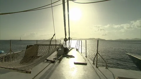 Sun over bow of Catamaran with hammock and land in distance 動画素材 95601356