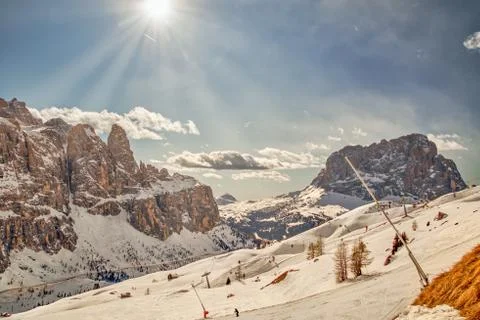 Sun over the ski slopes in front of the rock formations called sella towers a Stock Photos