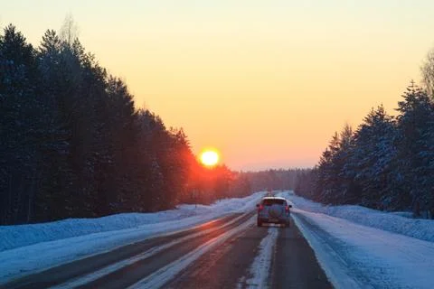 The sun over the winter forest highway at sunrise in frosty morning Stock Photos