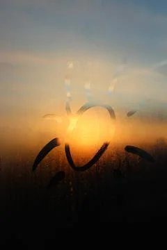 The sun painted on a fogged window under the light of sunset Foto stock