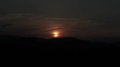 Sun Partially Obscured by Eclipse Over Hills in Dramatic Darkened Sky Stock Footage 344440494