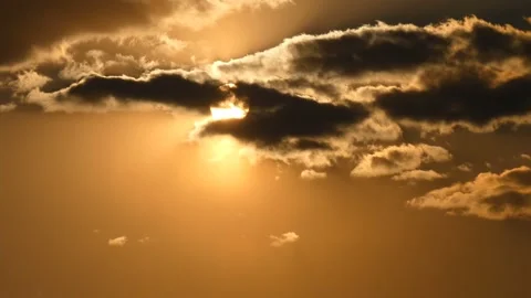 Sun passes through dramatic gray clouds on a golden sky during sunset Stock Footage 248141812
