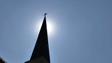 Sun peaking out from behind silhouetted church steeple Stock Footage 116181160