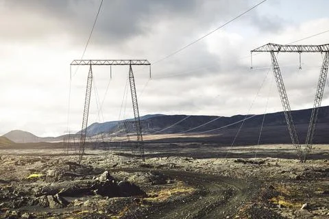 Sun peaking out from the clouds shining on electrical lines running trough Stock Photos