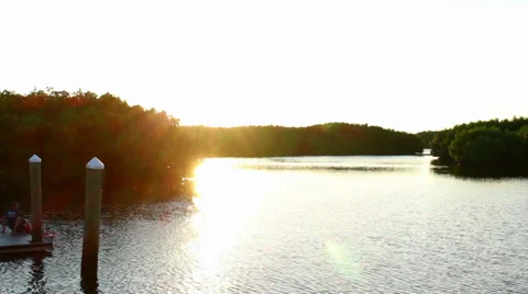 Sun peeking around the trees over the river 스톡 동영상 32186356