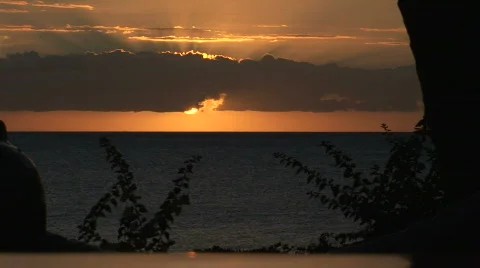 Sun peeking below clouds on ocean Видео 340545