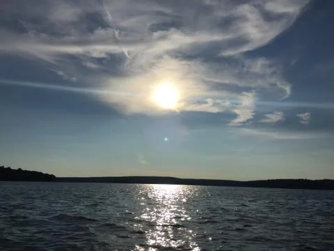 Sun peeking through clouds above lake Foto stock