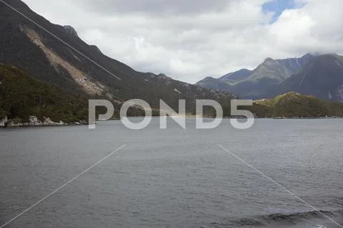 Sun peeking through the clouds at Doubtful Sound. Stock Photos