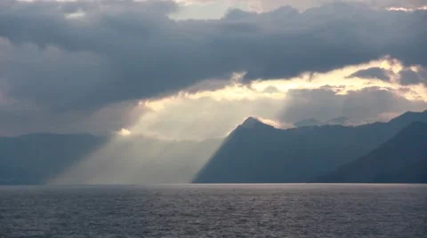 Sun Peeking through the Clouds during Mountain Lake Sunset Stock Footage 50667399