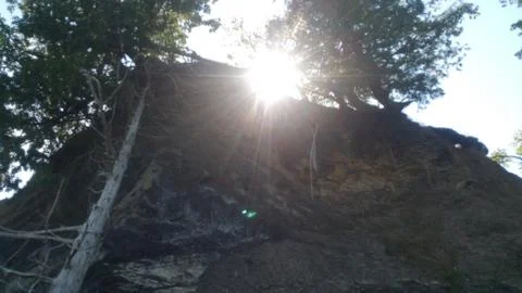 Sun peeking through the trees on a rock ledge on a peninsula on the lake Foto stock