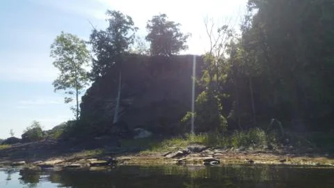 Sun peeking through the trees on a rock ledge on a peninsula on the lake Foto stock
