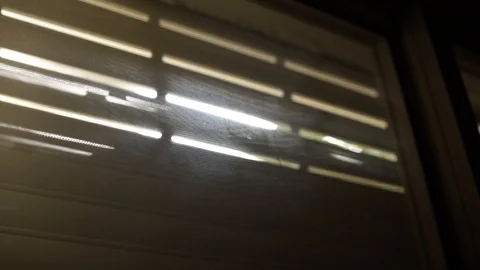 Sun peeks inside as window shutters rolls up to open Stock Footage 101460494