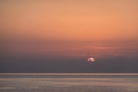 Sun peeks out from clouds during sunrise at the red sea Stock Photos
