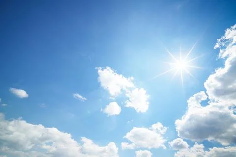 Sun peeks through clouds in blue sky, creating a picturesque natural landscap Stock Photos