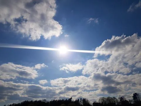 The sun peeks through the clouds. Cloudy blue sky. Bright sun in a blue sky Stock Photos